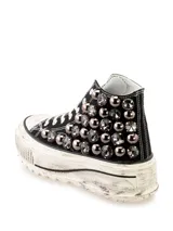 Zapatilla tipo bota de lona negra con plataforma blanca de aspecto desgastado y apliques de strass y tachas plateadas en los laterales.