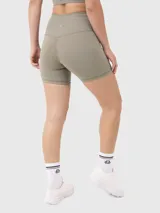 Conjunto deportivo de dos piezas compuesto por un top de un solo hombro y un short biker de tiro alto con cintura cruzada en forma de V. Confeccionado en tejido elástico de alta compresión.