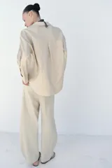 Blusa amplia confeccionada en mezcla de viscosa y lino, color beige, con cuello solapa, escote en V y manga larga.