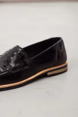 Mocasín de cuero vacuno en color marrón, con diseño bitono que combina texturas lisas y con grabado tipo cocodrilo en el empeine. Cuenta con detalle de estribo clásico y suela plana con vira en contraste.