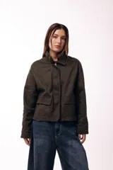 Campera corta color marrón, con cuello alto estructurado, cierre frontal y bolsillos delanteros con solapa. Presenta puños y cuello en tejido acanalado, con un diseño de corte recto y minimalista.