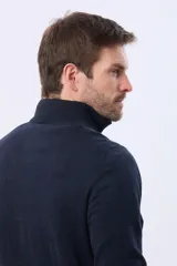 Buzo tejido de punto color verde oscuro, con cuello alto y cierre frontal parcial. Presenta un detalle en cuero en el tirador del cierre y un pequeño logo bordado en el pecho.