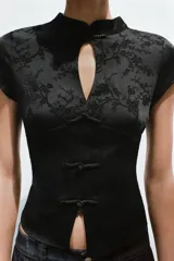 Top negro de manga corta y cuello mao con diseño jacquard de flores, escote en pico y cierre frontal con alamares.