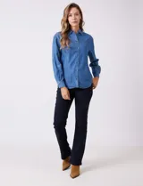 Camisa de tencel azul, marca Weekend Routine, con cuello solapa, botones metálicos frontales y manga larga regulable con presilla y botón. Presenta canesú horizontal en la espalda con tablón central y bajo asimétrico redondeado.