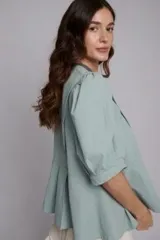 Chaqueta de corte femenino en color verde agua, con mangas abullonadas y diseño con volados en la parte inferior. Presenta bordados artesanales a mano y cierre frontal.