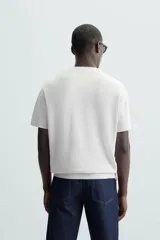 Camiseta negra de punto perlado, corte regular fit, cuello redondo, manga corta y rib en los acabados.