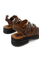 Sandalias de cuero color marrón chocolate, con tres tiras horizontales con ojales y hebillas metálicas plateadas. Suela de goma negra con plataforma.