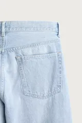 Jeans de denim de algodón en color azul con efecto desgastado, tiro medio y corte recto de ajuste holgado (loose fit). Cuenta con diseño clásico de cinco bolsillos y cierre frontal con cremallera y botón.