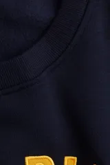 Buzo de tejido liso color azul marino, con cuello redondo y puños y bajo acanalados. Presenta un diseño bordado en amarillo en el frente con el texto "MONTE BIANCO ITALY 4805".