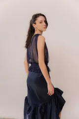 Pollera midi de tafeta color azul marino, de tiro alto con detalle de volados en la cintura y en el ruedo, aportando gran volumen y movimiento.