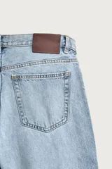 Pantalón jeans de corte recto, color celeste claro con efecto lavado, de cinco bolsillos y tiro medio.