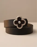 Cinto de cuero negro con hebilla plateada en forma de trébol de cuatro hojas, decorada con esmalte negro brillante y un detalle metálico esférico en el centro.