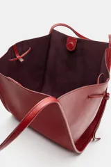 Bolso tipo shopper color rojo de hombro, con detalle de lazos en los laterales y doble asa.