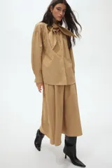 Camisa de corte relajado en tejido dobby con estampado de cuadros, cuello con detalle de moña y botonadura frontal. Presenta hombros caídos y mangas largas con puños abotonados.