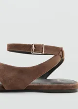 Sandalias planas de gamuza marrón, con diseño de tiras cruzadas, separador de dedo y tira ajustable en el tobillo con hebilla metálica.
