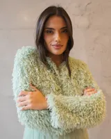 Chaqueta cropped de textura peluda en color verde agua, con diseño de manga larga y acabado suave. Ideal para complementar outfits de ocasión.