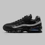 Zapatilla deportiva Nike Air Max 95, color negro con capas superpuestas en tonos grises y plateados reflectantes. Presenta unidades Air Max visibles en el antepié y el talón, con una unidad de aire en el talón con tinte azul.