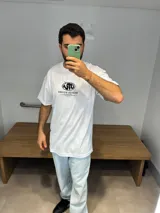 Remera blanca de algodón premium, corte oversize, con estampado en serigrafía en la espalda con logo y listado de ciudades.