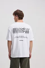 Remera oversize de manga corta color marrón con estampa pequeña en el pecho y estampa geométrica en la espalda.