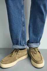 Zapato de cordones con parte superior de piel con acabado en serraje, detalle de bordón en el empeine, horma redonda y suela a contraste.