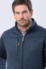 Campera de tejido texturado en color azul, con interior de polar, cuello alto, cierre frontal completo y bolsillo vertical en el pecho con detalle de tirador de cuero sintético.