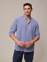 Camisa de manga larga para hombre, confeccionada en algodón con efecto peach (textura suave). Presenta un estampado de cuadros vichy en tonos azul marino y blanco, cuello con botones y un bolsillo de parche en el pecho izquierdo.