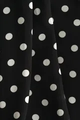 Top de corte holgado en tejido transparente con escote halter y cuello alto estilo pañuelo con cierre de botón en la nuca. Presenta un diseño con estampado de lunares y forro interior.
