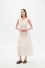 Vestido midi de lino color beige con diseño a cuadros discretos, cuello cuadrado, sin mangas y con cinturón ajustable en la cintura.