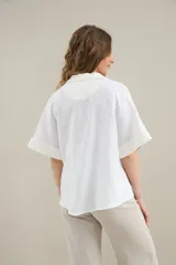 Blusa blanca de lino con silueta cómoda y relajada, escote en V con cuello polo y detalles en algodón.