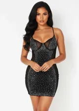 Vestido corto ajustado tipo bodycon, color negro, con paneles laterales de malla transparente y copas estructuradas. Presenta un diseño decorado con pedrería brillante distribuida por toda la parte frontal y el busto, con breteles finos.