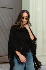 Poncho triangular de lana en color crudo, con diseño de tejido texturizado y terminaciones de flecos largos en todo el borde.