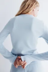 Saco de punto con textura tipo waffle, color celeste, de ajuste entallado, cuello redondo y cierre frontal con botones.