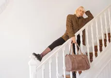 Bolso de mano tipo shopper marca Amadea, confeccionado en cuero con acabado desgastado. Presenta detalles de costuras decorativas verticales, correas con hebillas metálicas doradas y logo grabado al frente.