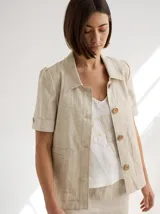 Chaqueta de lino color beige, con cuello camisero, manga corta y cierre frontal con botones de madera.