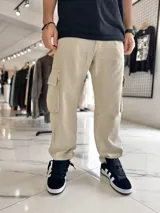 Pantalón cargo de jean corte baggy, color arena, con bolsillos laterales con solapa en las piernas y diseño ancho.