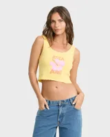 Top musculosa Billabong de corte crop en color amarillo, con diseño estampado frontal de flor tropical y texto en tonos rosados y naranjas.