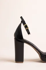 Sandalias de tacón alto con plataforma, confeccionadas en cuero con acabado brillante tipo charol, color negro. Poseen tira delantera ancha, tira ajustable al tobillo con hebilla metálica dorada, y taco ancho.