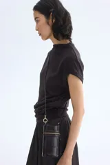 Top de punto fino color negro, con cuello elevado corto, mangas cortas con dobladillo y detalle de pliegues drapeados en un lateral de la cintura.