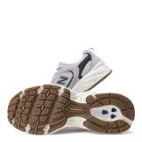 Championes New Balance 530 de estilo urbano, confeccionados en malla gris y superposiciones de gamuza en tono lila. Cuentan con detalles en negro, entresuela blanca ABZORB y suela de goma con tacos marrones.