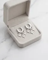 Aros tipo argolla pequeña de acero con tres dijes colgantes en forma de árbol de la vida.