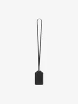 Llavero con funda de cuero negra en forma de casa, con correa para colgar al cuello. Incluye una llave plateada.
