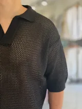 Chomba de tejido abierto color blanco, de manga corta, con cuello polo y escote en V.
