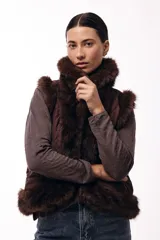 Chaleco acolchado color marrón con terminaciones de piel sintética en los bordes y cuello, aportando volumen y textura.