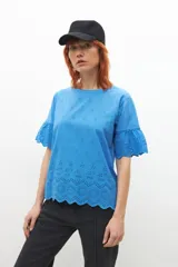 Remera celeste con broderie, de mangas cortas con volados.