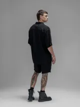 Camisa de corte oversize color negro, confeccionada en lino, con cuello tipo cubano, cierre frontal de botones y mangas cortas.