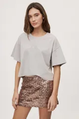 Remera gris de fit amplio, con mangas cortas y cuello redondo. Presenta efecto lavado y estampa frontal con aplicación de strass con la frase "fiesta mode on".