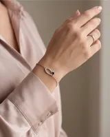 Pulsera de plata 925 con diseño de herradura adornada con circonias brillantes y un pequeño detalle de trébol negro en el centro.