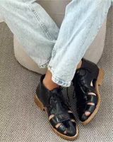 Zapato acordonado de cuero vacuno color marrón con aberturas laterales y cordones negros.