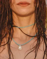Collar con cordón celeste y dije de perla irregular con engarce de plata.