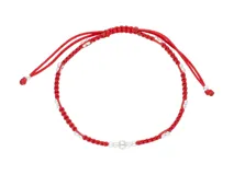 Pulsera de hilo rojo anudado en macramé, con pequeñas esferas de plata 925 intercaladas y un dije central de plata con forma de ojo o figura abstracta. Posee terminaciones ajustables con nudos corredizos.